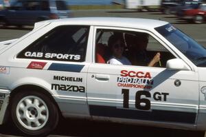 Jean Lindamood flashes a smile from the passenger seat of Shannon Millen's Mazda 323GTX.