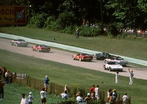 11) Peter Lockhart's and 18) Andy Pilgrim's Chevy Corvettes tangle coming out of turn 5 as traffic weaves past.