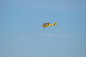 A Piper Cub flies over the track
