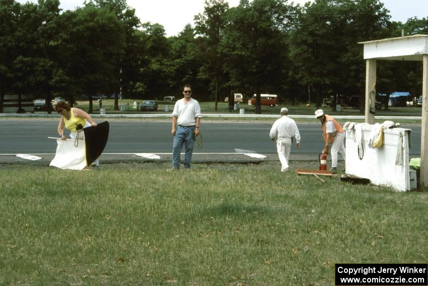 Kathy Maleck, John Dahlmeier, and others clean up the corner 10 flagstand at the end of the day.