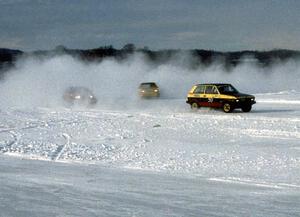 Pat Whitney's Yugo is followed by two other cars onto the front straight.