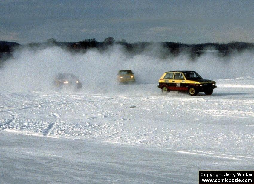 Pat Whitney's Yugo is followed by two other cars onto the front straight.