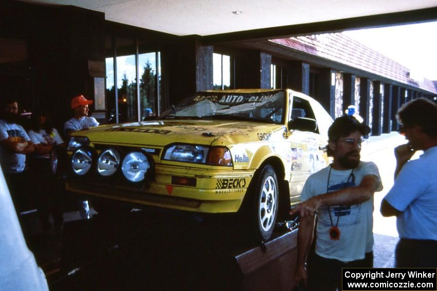 Tom Gillespie explains his roll with navigator Rick Beson in his Mazda 323GTX to a local bystander.