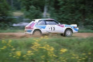 The Peter Moodie / Mike Fennell Mazda 323GTR powers away from spectators at the county road.