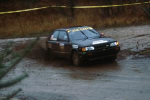Rees Harris / Constantine Manotopoulos in their Mazda 323GTX sling gravel at the Delaware delta.