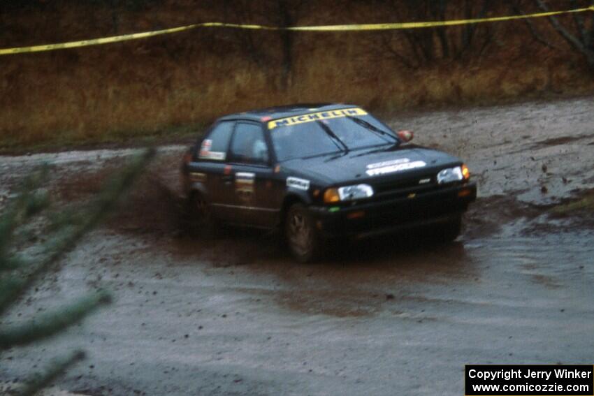 Rees Harris / Constantine Manotopoulos in their Mazda 323GTX sling gravel at the Delaware delta.