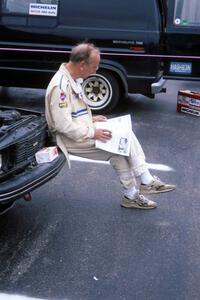 Stuart Spark reads over a copy of the NINES newsletter on the bumper of the SAAB 99EMS he and Jerry Sweet shared.