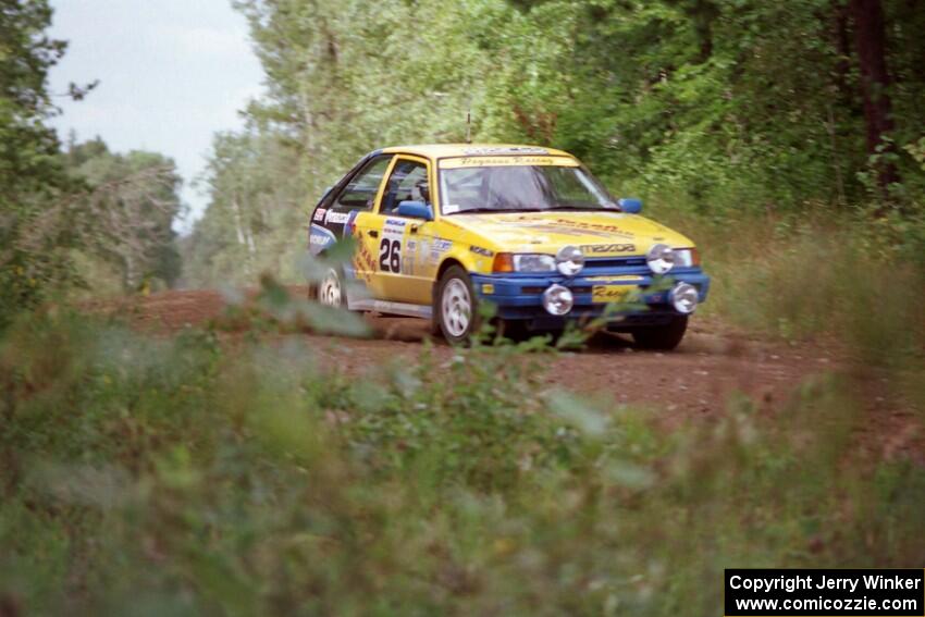 The David Ralakis / Tom Gillespie Mazda 323GTX comes over a crest and into the spectator location in the Two Inlets SF.
