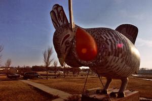 Giant Prairie Chicken statue in Rothsay, Minnesota with racecar in the background