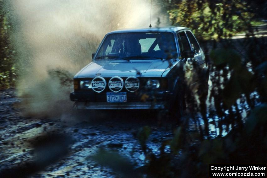 The VW Rabbit of Heikke Nielsen / Bob Nielsen hits a puddle before the final Menge Creek bridge.