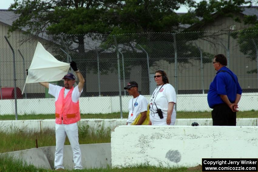 Corner workers at turn 6 display the white flag for an emergency vehicle on the track