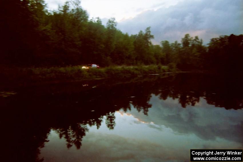 Leon Styles / John Dillon Mitsubishi Lancer Evo VII reflected against a lake on SS4, Blue Trail.