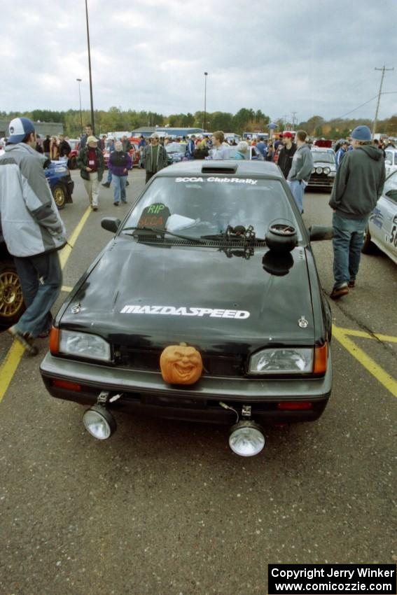 Tom Ottey / Pam McGarvey Mazda 323GTX at parc expose in Houghton. Note the R.I.P. SCCA sign.