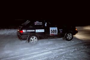 The Tom Ottey / Pam McGarvey Mazda 323GTX drifts through the first corner of the evening running of the ranch stage.