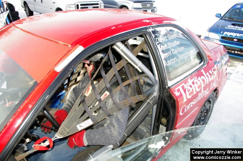 Brent Carlson straps into the driver's seat of the #84 Subaru Impreza
