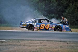 Bob Senneker throws sand onto an engine fire on his Ford Thunderbird