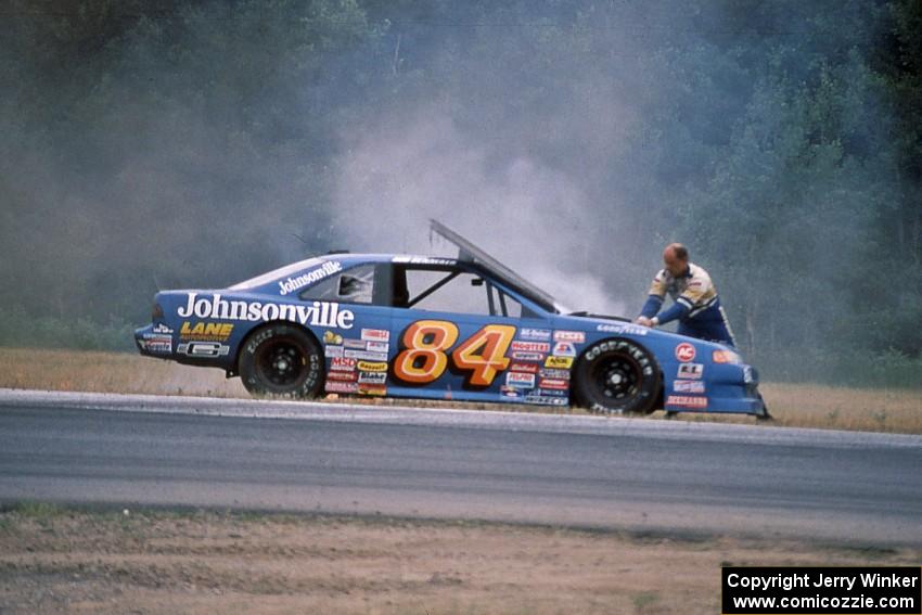Bob Senneker throws sand onto an engine fire on his Ford Thunderbird