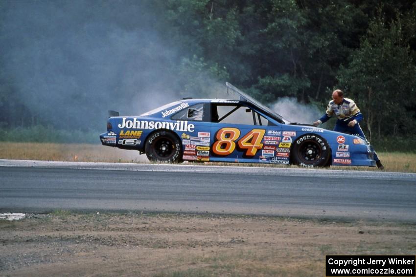 Bob Senneker throws sand onto an engine fire on his Ford Thunderbird