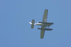 A plane takes off from a nearby lake and circles the track.