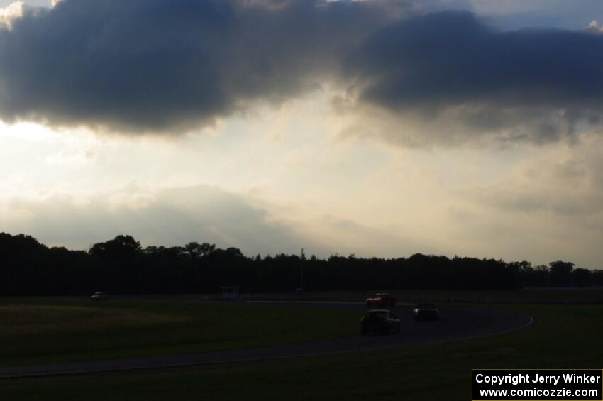 Four cars head through turn 4 into 5 about an hour before sundown.