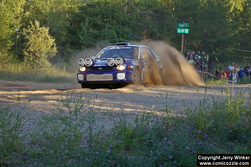 Tanner Foust / Chrissie Beavis Subaru WRX throws a wave of gravel over the car at the SS14 spectator point.